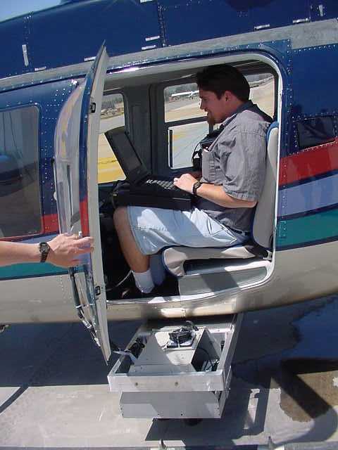 Staff researcher Lloyd (Pete) Coulter sitting in a helicopter on the tarmack and operating the ADAR 5500 multispectral camera system
